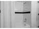 Bathroom featuring a white tiled shower with a bathtub and black accent stripe at 4899 S Dudley St # 3A, Littleton, CO 80123