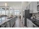 Bright, open kitchen featuring gray cabinets and stainless steel appliances, with an open view to the dining area at 6956 S Titus St, Aurora, CO 80016