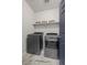 Modern laundry room featuring gray washer and dryer, marble floors, and floating shelves with decorative baskets at 6956 S Titus St, Aurora, CO 80016