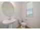 Bright powder room with pedestal sink, round mirror and wood-look tile flooring at 26789 E Cedar Ave, Aurora, CO 80018