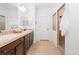 Bathroom with a double vanity, dark wood cabinets, neutral tile, and a walk-in shower at 19543 E 54Th Ave, Denver, CO 80249