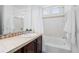 Bathroom featuring white tile, dark vanity and bathtub with shower at 19543 E 54Th Ave, Denver, CO 80249