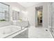 Bright bathroom featuring marble flooring, soaking tub, and a glass-enclosed shower with neutral color palette at 17720 W 94Th Dr, Arvada, CO 80007