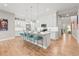 Bright kitchen featuring white cabinets, a large island with bar seating, and pendant lighting over light wood-look floors at 17720 W 94Th Dr, Arvada, CO 80007