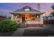 Charming brick home featuring a cozy front porch, well-manicured landscaping, and warm exterior lighting at 3928 Zuni St, Denver, CO 80211