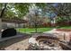 Expansive backyard with a covered patio, landscaped fire pit, large grassy area, and mature trees at 9325 Lark Sparrow Dr, Highlands Ranch, CO 80126