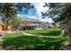Well-maintained backyard with lush lawn, mature trees, fire pit, and a charming walkway at 9325 Lark Sparrow Dr, Highlands Ranch, CO 80126
