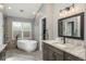 Bright bathroom featuring a soaking tub, tile floors, modern fixtures, and a dark vanity with solid countertops at 9325 Lark Sparrow Dr, Highlands Ranch, CO 80126