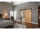 Spacious main bedroom with barn door leading to bathroom, an area rug, a ceiling fan, and lots of natural light at 9325 Lark Sparrow Dr, Highlands Ranch, CO 80126
