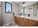 Bathroom featuring double sinks, a large mirror, a window, and wooden cabinets at 1711 Spring Water Ln, Highlands Ranch, CO 80129