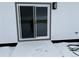 Back entrance view of patio sliding door entrance featuring gray trim on a white wall and a snowy patio at 61400 E 56 Ave, Strasburg, CO 80136