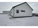 Side view of white modern home with black roof and gray trim in a snowy landscape at 61400 E 56 Ave, Strasburg, CO 80136