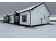 Exterior view of a modern white home with black trim and gray shutters in a snowy landscape at 61400 E 56 Ave, Strasburg, CO 80136