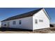 Side view of new home featuring white siding, black trim, grey windows and dark roof at 61400 E 56 Ave, Strasburg, CO 80136
