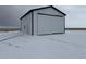 Storage building view featuring a white building with black roof and a large roll-up door at 61400 E 56 Ave, Strasburg, CO 80136