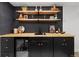 Basement bar area with wooden countertop and shelving, black cabinets, and beverage refrigerator, great for entertaining at 365 S Xapary St, Aurora, CO 80012