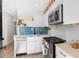 Well-lit kitchen with blue backsplash, stainless steel appliances, white cabinets, and floating wood shelves at 120 W Bayaud Ave, Denver, CO 80223