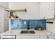 Modern kitchen with blue backsplash, stainless steel sink, quartz countertops, and floating wood shelves at 120 W Bayaud Ave, Denver, CO 80223