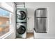 Bright laundry room featuring a stacked washer and dryer set next to a stainless steel refrigerator at 120 W Bayaud Ave, Denver, CO 80223
