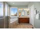 Bright bathroom featuring a soaking tub under a window and a double sink vanity with cherry wood cabinets at 3519 Zane Gray Loop, Parker, CO 80138