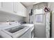 Bright laundry room featuring white cabinets, modern washer and dryer, and a window with curtains at 6307 Monterey Pl, Highlands Ranch, CO 80130