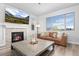 Cozy living room with a fireplace, modern furniture, and a large window providing natural light at 7315 Blue Water Dr, Castle Rock, CO 80108