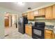 Classic kitchen featuring warm wood cabinets, black appliances and neutral countertops at 1495 S Chase Ct, Lakewood, CO 80232