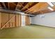 Unfinished basement with exposed wood ceiling, green carpet, and a window at 7715 Estes Ct, Arvada, CO 80005