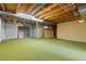 Unfinished basement space with an exposed ceiling, unfinished walls, and green carpet at 7715 Estes Ct, Arvada, CO 80005