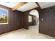 Spacious living room with wood walls, neutral carpet, arched doorway, a large window, and brick fireplace at 7715 Estes Ct, Arvada, CO 80005