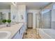 Bright bathroom featuring double sinks, shower, bathtub, and neutral tile floors at 15333 E 98Th Pl, Commerce City, CO 80022