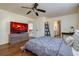 Relaxing main bedroom with ceiling fan, hardwood floors, and large TV at 15333 E 98Th Pl, Commerce City, CO 80022