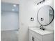 Updated bathroom with a new vanity, modern lighting and a view into the adjacent room at 19545 E Bates Ave, Aurora, CO 80013