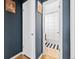 Hallway view leading to a well-lit bathroom with black and white accents and a shower-tub combo at 1221 Ulster St, Denver, CO 80220