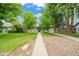 Inviting front yard with a well-maintained lawn and walkway leading to a charming home with mature trees at 1221 Ulster St, Denver, CO 80220