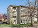 Exterior of a well-maintained apartment building with mature trees and landscaping at 9385 E Center Ave # 1B, Denver, CO 80247
