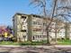 Multi-story condo building with mature trees and manicured lawn at 9385 E Center Ave # 1B, Denver, CO 80247