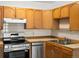 Kitchen with stainless steel appliances, wood cabinets, and neutral tile backsplash at 9385 E Center Ave # 1B, Denver, CO 80247