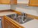 Close up of a stainless steel double sink with wood cabinets and tile backsplash at 9385 E Center Ave # 1B, Denver, CO 80247