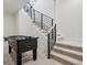 Modern staircase with black metal railing and light wood accents next to a foosball table at 6851 Copper Sky Cir, Castle Pines, CO 80108