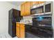 Efficient kitchen with black appliances, wooden cabinets, and clean white countertops at 2231 S Vaughn Way # 317 B, Aurora, CO 80014