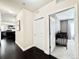 Open hallway leading into a living room with dark flooring and a bedroom with a crib and natural light at 12830 Jasmine St # A, Thornton, CO 80602