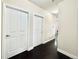 A bright hallway with dark wood floors, light walls, white trim, and several white doors at 12830 Jasmine St # A, Thornton, CO 80602