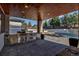 Outdoor kitchen featuring stone counters and stainless steel appliances under a wood paneled roof at 15902 W 64Th Ave, Arvada, CO 80007