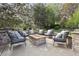 Backyard patio includes a fire pit with stone surround and built in bench seating among trees and landscaping at 14417 W 57Th Pl, Arvada, CO 80002