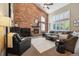 Cozy living room featuring a brick fireplace, large windows, and comfortable seating arrangement at 14417 W 57Th Pl, Arvada, CO 80002