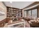 Well-lit home office with custom built-in shelving, a large desk, and comfortable seating at 14417 W 57Th Pl, Arvada, CO 80002