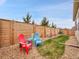 A backyard with a wooden fence, a small patch of green grass and a gravel area with red and blue adirondack chairs at 668 E Dry Creek Cir, Littleton, CO 80122