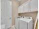This laundry room features a full-sized washer and dryer, bright lighting, and sleek, white cabinets for storage at 668 E Dry Creek Cir, Littleton, CO 80122