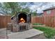 Close up of a stone oven in the backyard with a fire burning, next to a green garden at 45 Pierce St, Lakewood, CO 80226